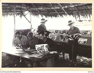 CAPE WOM, NEW GUINEA. 1945-09-29. TROOPS FROM VARIOUS UNITS OF HEADQUARTERS 6 DIVISION SELECTING READING MATERIAL FROM THE MAGAZINE FILES PROVIDED BY THE AUSTRALIAN ARMY EDUCATION SERVICE. ..