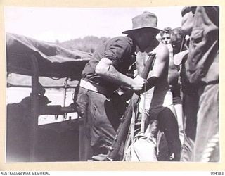 BOIKEN, NEW GUINEA. 1945-07-15. SICK MEMBERS OF 2/6 CAVALRY (COMMANDO) REGIMENT BEING TRANSFERRED TO A MOTOR LAUNCH WHICH WILL TAKE THEM TO CAPE WOM