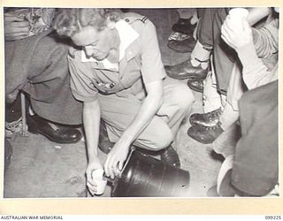 AIRBORNE, LAE, NEW GUINEA TO TOWNSVILLE, 1945-11-26. SISTER J. MENZIES, RAAF, POURING TEA FROM A THERMOS FLASK ABOARD AN AIRCRAFT OF 1 MEDICAL AIR EVACUATION TRANSPORT UNIT DURING THE EVACUATION OF ..