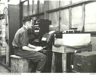 LAE, NEW GUINEA. 1944-04-03. WX2646 CORPORAL J.T. FLYNN, 19TH LINES OF COMMUNICATION SIGNALS OPERATING A TC 3 TELETYPE SWITCHBOARD AND TELETYPE MACHINE AT THE CARRIER TERMINAL