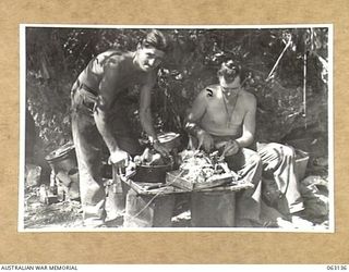 MASAWENG BEACH, NEW GUINEA. 1943-12-25. NX20445 PRIVATE J. HENDERSON (1) AND NX23594 CORPORAL A. C. PETTIT (2) COOKS OF THE 2/2ND MACHINE GUN BATTALION CARVING THE UNIT CHRISTMAS TURKEY AT THEIR ..