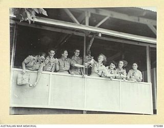 SOUTH ALEXISHAFEN, NEW GUINEA. 1944-08-08. SISTERS OF THE 111TH CASUALTY CLEARING STATION ENJOY SOME FUN WITH A BUNCH OF BANANAS ON THE VERANDAH OF THEIR HUT. IDENTIFIED PERSONNEL ARE:- WFX33605 ..