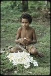 Girl making garland or lei of frangipani (plumeria) flowers