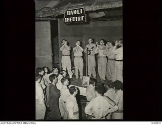 NADZAB, NEW GUINEA. C. 1944-02. THE MOUTH ORGAN BAND OF NO. 24 SQUADRON RAAF PERFORMING ON STAGE AT THE TIVOLI THEATRE WHILE THE DIVE BOMBER BOYS WATCH. LEFT TO RIGHT: SERGEANT S. CUSHAWAY, ..