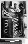 Priest and man preparing a printing press, Solomon Islands, Oceania, 1941