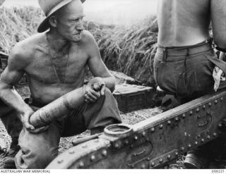 KUMBARUM, NEW GUINEA, 1943-10-23. VX19746 GUNNER R.R. PEART OF "F" TROOP, 54TH BATTERY, 2/4TH AUSTRALIAN FIELD REGIMENT ABOUT TO LOAD A 25-POUNDER GUN