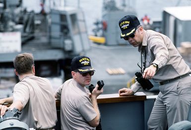 CAPT. A.L. Heisig, right, commanding officer, and CMDR. S. Markey, executive officer, confer on the bridge wing of the amphibious command ship USS BLUE RIDGE (LCC-19) as they monitor an underway replenishment operation with the fleet oiler USNS ANDREW J. HIGGINS (T-AO-190). The ships are operating in the waters off Saipan during Operation Tandem Thrust