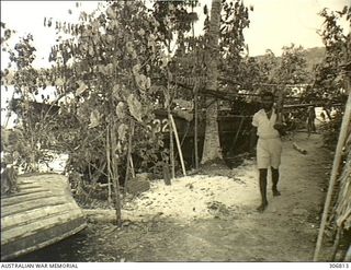 NEW GEORGIA, SOLOMON ISLANDS. 1943-03. A NATIVE SENTRY GUARDS A CAPTURED JAPANESE BARGE ALONGSIDE THE WHARF AT THE SEGI COASTWATCHERS STATION (ZGJ5) OF CAPTAIN D.G. KENNEDY, BRITISH SOLOMON ISLANDS ..