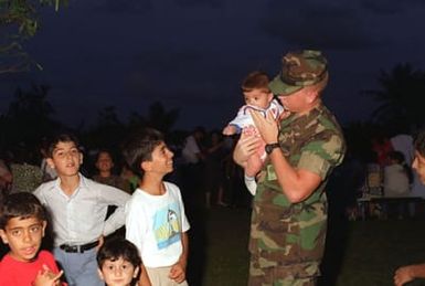 Lance CPL. David Bauman, 1ST Battalion, 6th Marines, hold a Kurdish new born baby during the festivities of Eid-af-altar. This is a Muslim tradition that celebrates the end of Ramadan, a month long holiday that entails fasting, and spiritual enlightenment