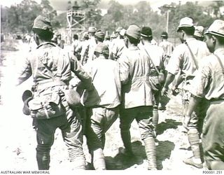 THE SOLOMON ISLANDS, 1945-09-19. JAPANESE SOLDIERS FROM NAURU ISLAND ASSISTING A SICK COMRADE AS THEY APPROACH AN INTERNMENT CAMP ON BOUGAINVILLE ISLAND. (RNZAF OFFICIAL PHOTOGRAPH.)