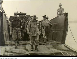 New Britain. 4 April 1945. The Commander-in-Chief of the Australian Military Forces, General Sir Thomas Blamey, and other members of his official party disembark from a landing barge at Waitavalo ..