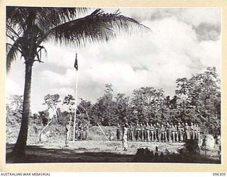 KAHILI, SOUTH BOUGAINVILLE. 1945-09-09. THE GUARD, AND LIAISON OFFICERS OF THE BUIN LIAISON GROUP, 2 CORPS, SALUTING DURING THE RAISING OF THE AUSTRALIAN FLAG AT BUIN