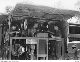 TOROKINA, BOUGAINVILLE, 1945-12-05. SIGNALMAN J. A. BUTLER (1), CRAFTSMAN R. BEESTON (2), SERGEANT K. THOMAS (3) AND WARRANT OFFICER 1 W. A. NEW (4), MEMBERS OF 1 DETACHMENT MOBILE CINEMA UNIT, ..