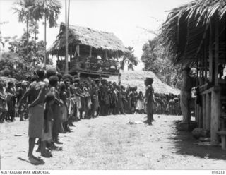 HOPOI, NEW GUINEA, 1943-10-20. NX155085 CAPTAIN R.G. ORMSBY OF THE AUSTRALIAN AND NEW GUINEA ADMINISTRATIVE UNIT ADDRESSING A LINE UP OF VILLAGE NATIVES TO TALK ON THE WAR AND APPEALING FOR THEIR ..