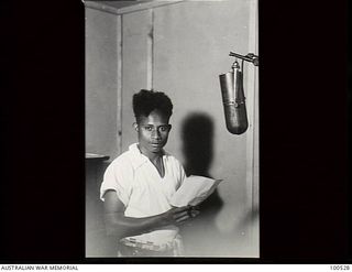 Port Moresby, New Guinea. 1944-07-22. Masi Igo, a Papuan native announcer, broadcasting from the Radio Station 9PA