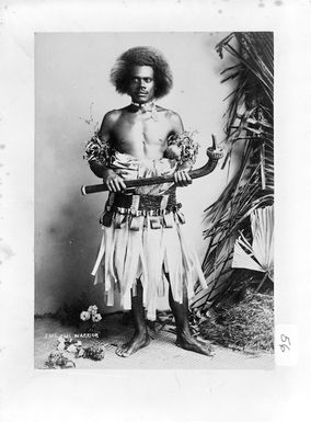 Unidentified Fijian warrior standing with a war club in hand