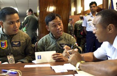 Captain Donato M. Aquino, (left), 220 Airlift Wing, Mactan Air Base, Philippine Air Force, and Major Nicolas C. Parilla, Headquarters Philippine Air Force (HPAF), receive assistance from MASTER Sergeant Horace Jordan Jr., USAF, Headquarters Pacific Air Force (HQ PACAF), concerning finances during their travel to Andersen Air Force Base, Guam. PACIFIC AIRLIFT RALLY (PAR) 2001 is a PACAF-sponsored Military Airlift symposium for countries in the pacific region. PAR, held every two years and hosted by a pacific nation, this year Guam is the host nation with the symposium staging out of Andersen AFB. The symposium includes informational seminars with area of expertise briefings, a Command Post...