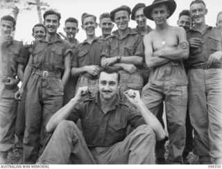 ULUNKOHOITU, YAMIL AREA, NEW GUINEA, 1945-07-18. PTE. R. CHARLESWORTH, 9 PLATOON, A COMPANY 2/6 INFANTRY BATTALION, THE WINNER OF A MOUSTACHE GROWING CONTEST, DISPLAYING THE "HANDLEBARS" OF HIS ..