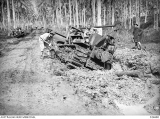 MILNE BAY, PAPUA. 1942-10. A BULLDOZER OF AN AUSTRALIAN UNIT HOPELESSLY BOGGED IN SOFT MUD NEAR GILI GILI ON THE SHORES OF MILNE BAY. FURTHER UP THE ROAD ON THE LEFT A TRUCK MAY BE SEEN ALSO WELL ..