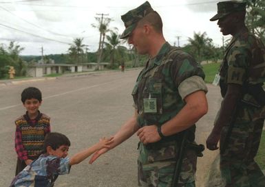 Lance CPL. William Kazy gets a low-five from a Kurdish evacuee while he and his partner Lance CPL. Derrell Cason walk their post during a Marine Joint Task Force operation