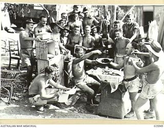 PORT MORESBY, PAPUA. 1942-07. NO MATTER WHERE HE IS, THE AUSTRALIAN SOLDIER ALWAYS TAKES A KEEN INTEREST IN SPORTING EVENTS AT HOME. HERE, MILITIAMEN FROM VICTORIA EAGERLY WATCH THE DRAWING OF A ..