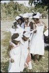 Dancers in white dresses with red trim, white handkerchiefs on head