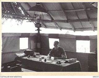 RABAUL, NEW BRITAIN, 1945-11-26. PRIVATE R.J. GODWIN, UNIT CLERK, 11 DIVISION, SALVAGE UNIT AT WORK IN THE OFFICE