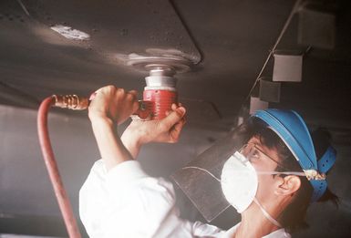 AIRMAN First Class Paula Heath of the 43rd Bombardment Wing Corrosion Control Branch grinds the stabilizer on an aircraft to prepare it for repainting