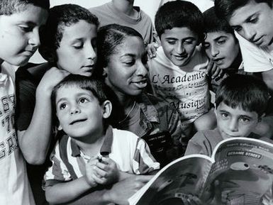 Military Photographer of the Year Winner 1997 Title: Reading Haven Category: Feature; Portfolio Place: 2nd Place Feature; 1ST Place Portfolio Exact Date Shot Unknown Caption: Kurdish children Gather around as AIRMAN 1ST Class Kerry Corley reads to them from a Sesame Street book. These children and their parents fled the tyranny of Saddam Hussein and found refuge on South Anderson AFB during Operation Pacific Haven