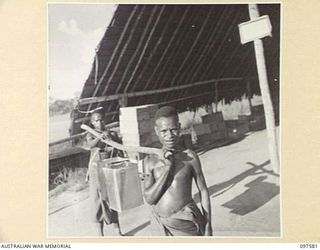 MAPRIK, NEW GUINEA. 1945-10-04. TWO AUSTRALIAN NEW GUINEA ADMINISTRATIVE UNIT NATIVES USING AN EASIER WAY OF CARRYING WATER TO THE TROOPS