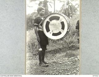 MILNE BAY, PAPUA, NEW GUINEA. 1944-04-01. A MEMBER OF HEADQUARTERS ROYAL PAPUAN CONSTABULARY, IN THE SAMARAI DISTRICT WITH A BASE DRUM. A SET OF DRUMS WAS PRESENTED TO THE UNIT BY THE AUSTRALIAN ..