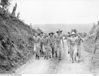 MILNE BAY, NEW GUINEA. 1943-07-12. MEMBERS OF THE 17TH PLATOON, "D" COMPANY, 2/1ST AUSTRALIAN PIONEER BATTALION, AIF, TRUDGE UP HILL STATION ROAD, AFTER A DAY'S WORK. LEFT TO RIGHT:- NX69339 ..