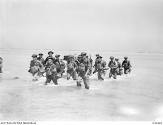 AITAPE, NORTH EAST NEW GUINEA. C. 1944-12-25. MEMBERS OF THE RAAF SIGNALS UNIT WITH PORTABLE EQUIPMENT WADING ASHORE TO THE BEACH-HEAD
