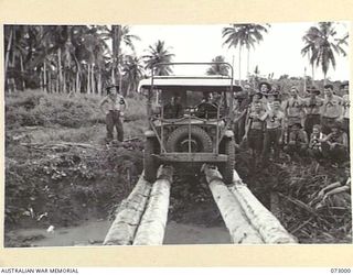 MADANG, NEW GUINEA. 1944-04-25. A JEEP, MODIFIED TO CARRY AN ADDITIONAL LOAD, CROSSES A BOMB CRATER ON A TEMPORARY BRIDGE CONSTRUCTED BY ROYAL AUSTRALIAN ENGINEERS. THE CRATER, CAUSED BY AN RAAF ..