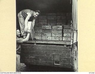 PORT MORESBY, NEW GUINEA. 1944-04-18. SX25549 PRIVATE C.S. YOUNG (1), AND SX30836 PRIVATE M.W. READ (2), MEMBERS OF THE AUSTRALIAN ARMY SERVICE CORPS, LOAD CASES OF BONELESS BEEF FROM A COLD STORE ..