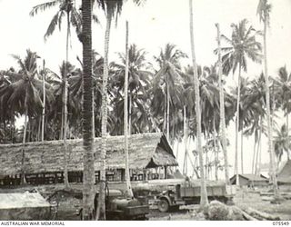 MADANG, NEW GUINEA. 1944-08-29. THE MEN'S MESS BUILDING IN THE MADANG BASE SUB-AREA. THE WELL IN THE FOREGROUND IS 15 FEET DEEP AND HAS A CAPACITY OF SOME 400 GALLONS PER DAY