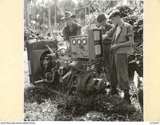 ALEXISHAFEN AREA, NEW GUINEA. 1944-04-27. SIGNALLERS FROM THE 8TH INFANTRY BRIGADE SALVAGING USABLE PARTS, (PARTICULARLY GAUGES AND METERS), FROM AN ABANDONED JAPANESE GENERATOR ON THE MADANG - ..