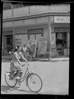 Street scene with young woman riding bicycle, Papeete, Tahiti