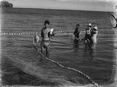 [View of Pacific Island people standing in the sea]