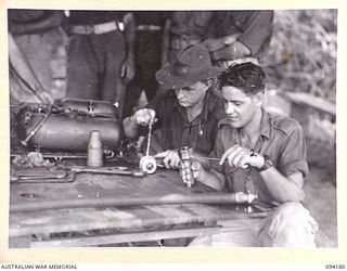 BOIKEN, NEW GUINEA. 1945-07-15. LANCE CORPORAL M.B. MCDONALD (1) AND SERGEANT AMOUR, 2/7 COMMANDO SQUADRON (2), FITTING THE GUN SECTION OF A FLAME-THROWER TOGETHER AT 2/6 CAVALRY (COMMANDO) ..