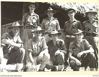 KAMALGAMAN ANCHORAGE, JACQUINOT BAY, NEW BRITAIN. 1944-12-23. PX170 MAJOR A.A. ROBERTS, AUSTRALIAN NEW GUINEA ADMINISTRATIVE UNIT DISTRICT OFFICER (7) AND HIS STAFF OUTSIDE THE UNIT OFFICE AT ..