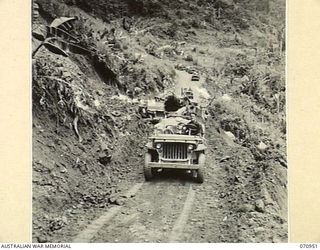 ZENAG, NEW GUINEA, 1944-02-27. A JEEP AND TRAILER CONVOY CONTINUING ALONG THE ROAD FOURTY EIGHT AND A HALF MILES FROM WAU AFTER THE SURFACE HAD BEEN CLEARED FROM A LNADSLIDE BY A D6 ANGLE DOZER ..