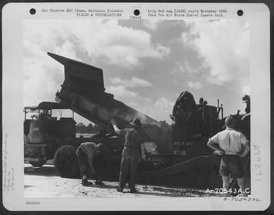 A Dump Truck Empties Its Load Of Smoking Hot Aspalt Into The Tray Of The Aspalt Spreader At The Runway Which The 72Nd See Bees Are Building For The 11Th Bomb Group On Agana Field, Guam, Marianas Islands. October 10, 1944. (U.S. Air Force Number A70543AC)