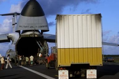 Members of the 22nd Military Airlift Squadron and local Samoans unload a tractor-trailer containing an electrical generator and supplies from the front end of a C-5 Galaxy aircraft at the Pago Pago International Airport