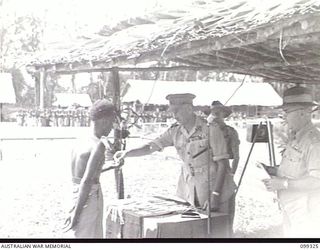 TOROKINA, BOUGAINVILLE, 1945-12-04. MAJOR-GENERAL W. BRIDGEFORD, GENERAL OFFICER IN CHARGE 3 DIVISION, PRESENTING IAGA, A NATIVE SCOUT, WITH A MEDAL FOR MERITORIOUS SERVICE DURING A MEDAL ..