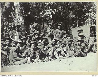 KARAWOP AREA, NEW GUINEA. 1945-04-21. DUSTY, GRIMY-FACED ARTILLERYMEN FROM 2/2 FIELD REGIMENT, ROYAL AUSTRALIAN ARMY, DRINKING TEA OUTSIDE A SALVATION ARMY STALL AS THEIR UNIT MOVES FORWARD TO ..