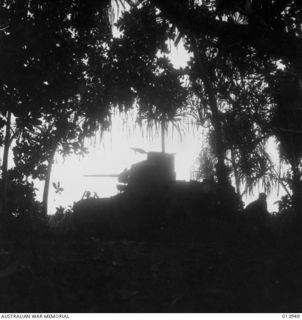 1942-12-28. PAPUA. SILHOUETTED AGAINST THE RISING SUN, AN AUSTRALIAN TANK MOVES THROUGH HEAVY FOLIAGE TO ATTACK THE JAPANESE POSITIONS AT BUNA. (NEGATIVE BY G. SILK)