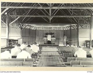 LAE, NEW GUINEA. 1944-11-26. VX0041 CHAPLAIN A.L. RUBY, CHURCH OF ENGLAND, CONDUCTING THE SERVICE OF HOLY COMMUNION IN THE NEW CHAPEL AT THE LAE BASE SUB AREA. AS A RESULT OF THE IRREPARABLE DAMAGE ..