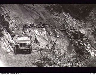 REINHOLD HIGHWAY, NEW GUINEA. 1943-08-25. CONVOY FROM HEADQUARTERS, ROYAL AUSTRALIAN ENGINEERS, 11TH AUSTRALIAN DIVISION ON THE BENCHING OF A ROCK FACE, IN THE ELOA RIVER AREA