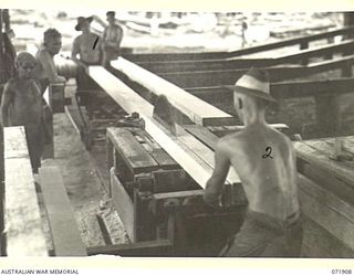 LAE, NEW GUINEA. 1944-03-30. NX163900 SAPPER C. BUNNER (1), WITH VX112376 SAPPER W. ANGOVE (2), WORK AT NO. 1 BENCH SAW IN THE SAWMILL AT THE 59TH CORPS FIELD PARK COMPANY. THE MILL HAS PRODUCED ..